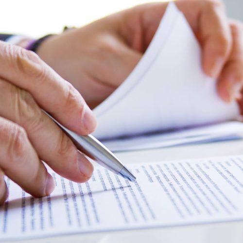 hands of business man in dark suit writing in his datebook