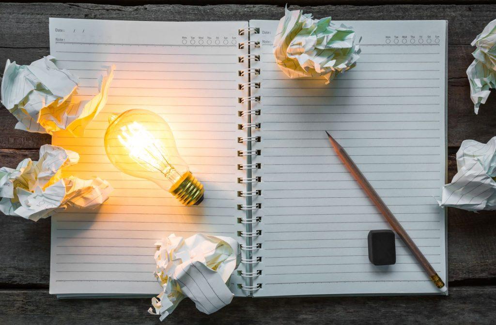 note book and light bulb on wood table
